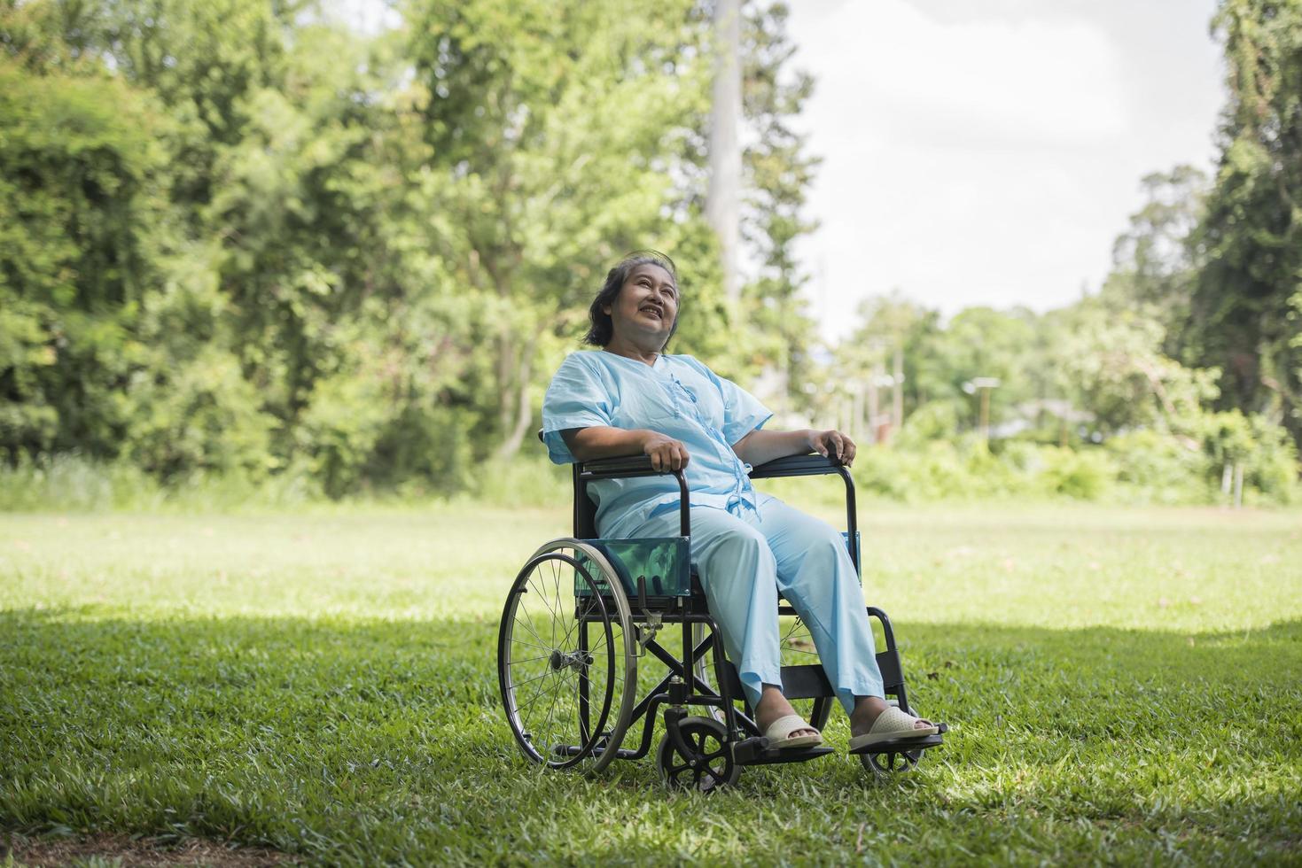 Anciana solitaria sentada en silla de ruedas en el jardín en el hospital foto