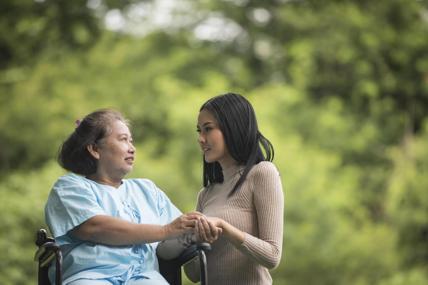 nieta hablando con su abuela sentada en silla de ruedas foto