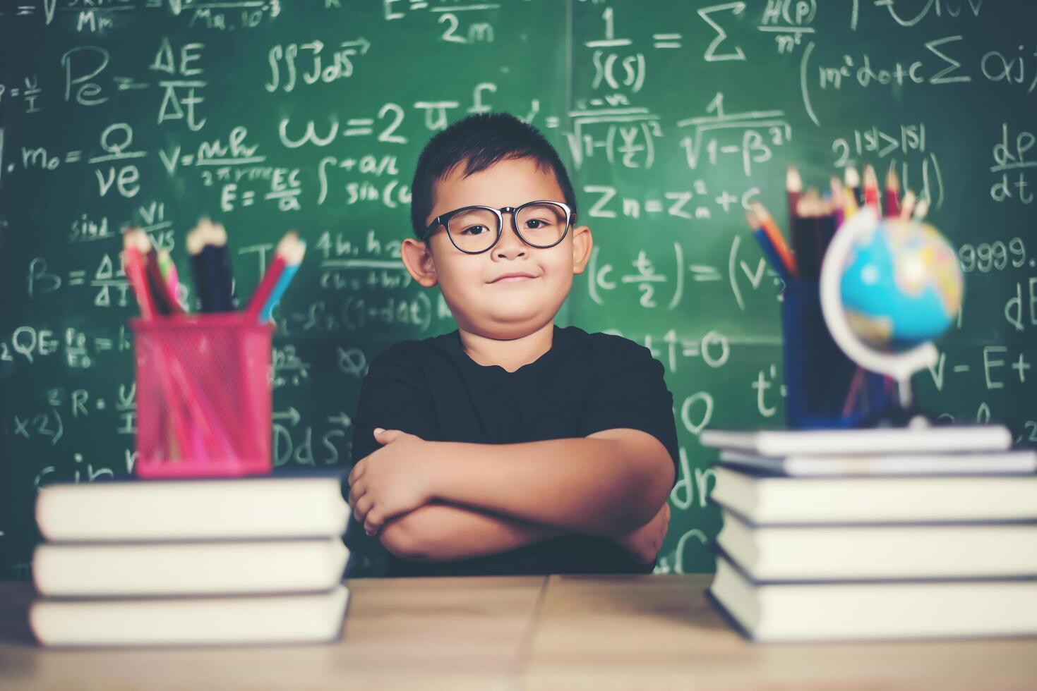 Thoughtful little boy with book near a school board photo