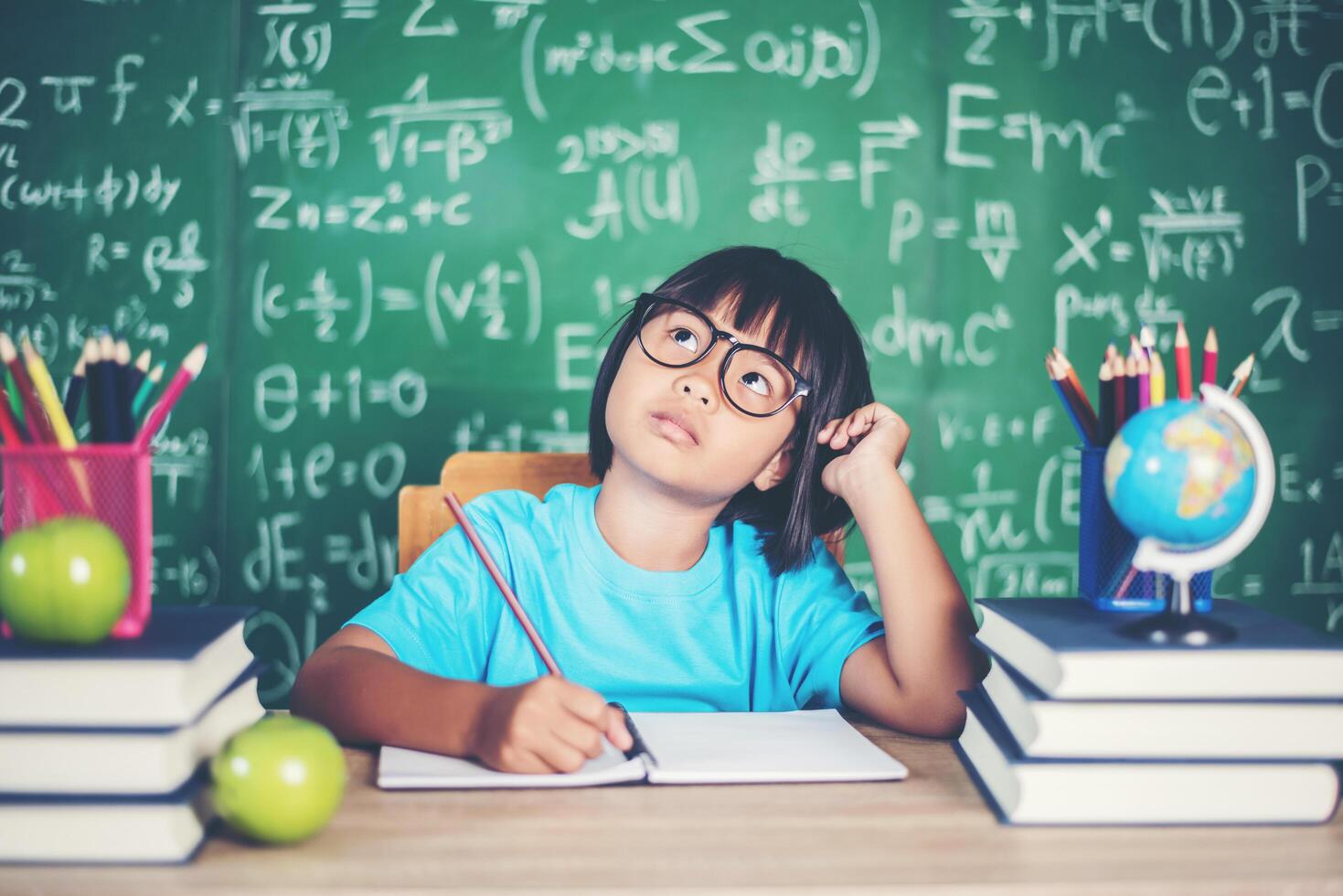 niña pensativa con libro cerca de una junta escolar foto