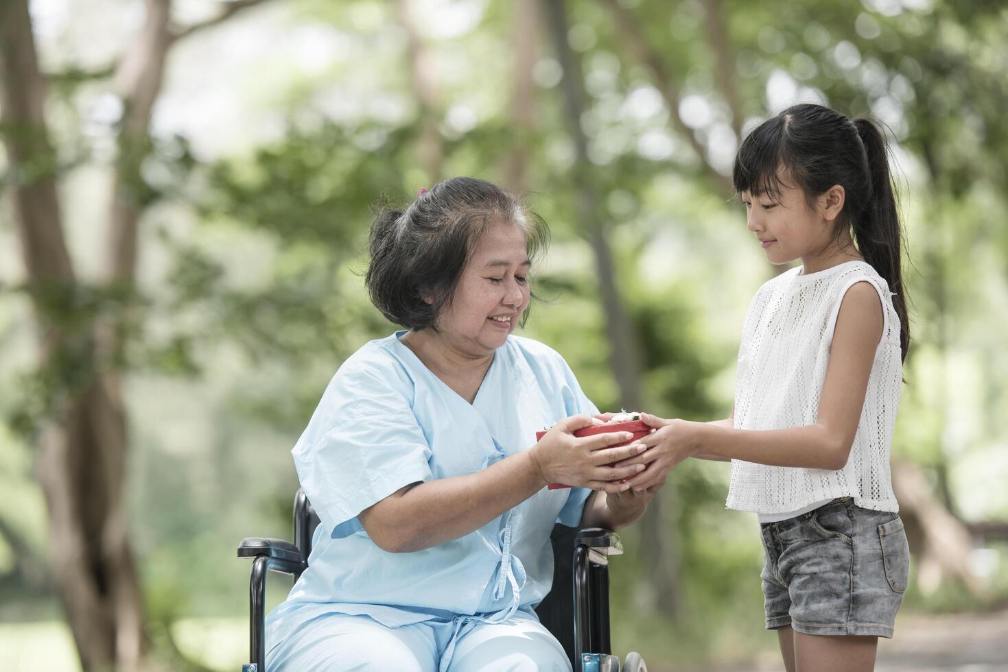 Granddaughter have surprise to grandmother sitting on wheelchair. photo