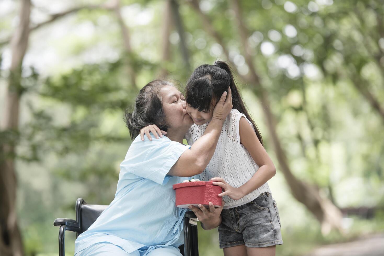 Granddaughter have surprise to grandmother sitting on wheelchair. photo