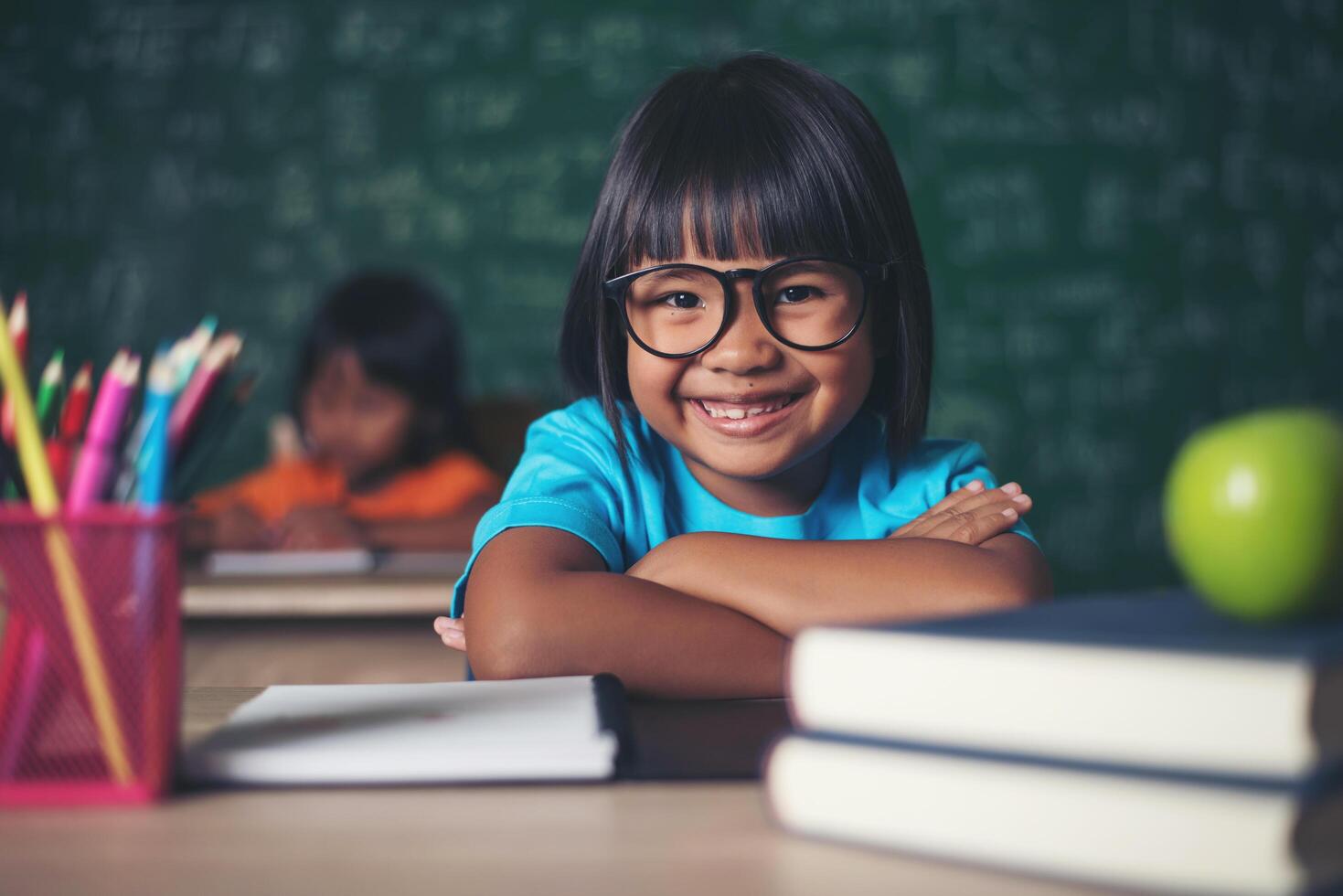 Portrait of smiling schoolgirl sitting at the table with books photo