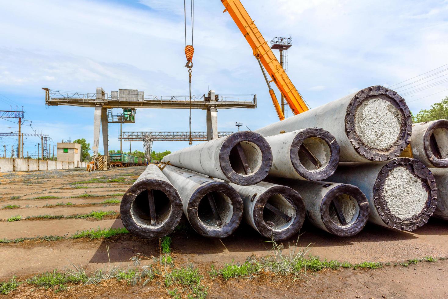 Unloading of concrete high-voltage poles at the construction site using a lifting crane photo