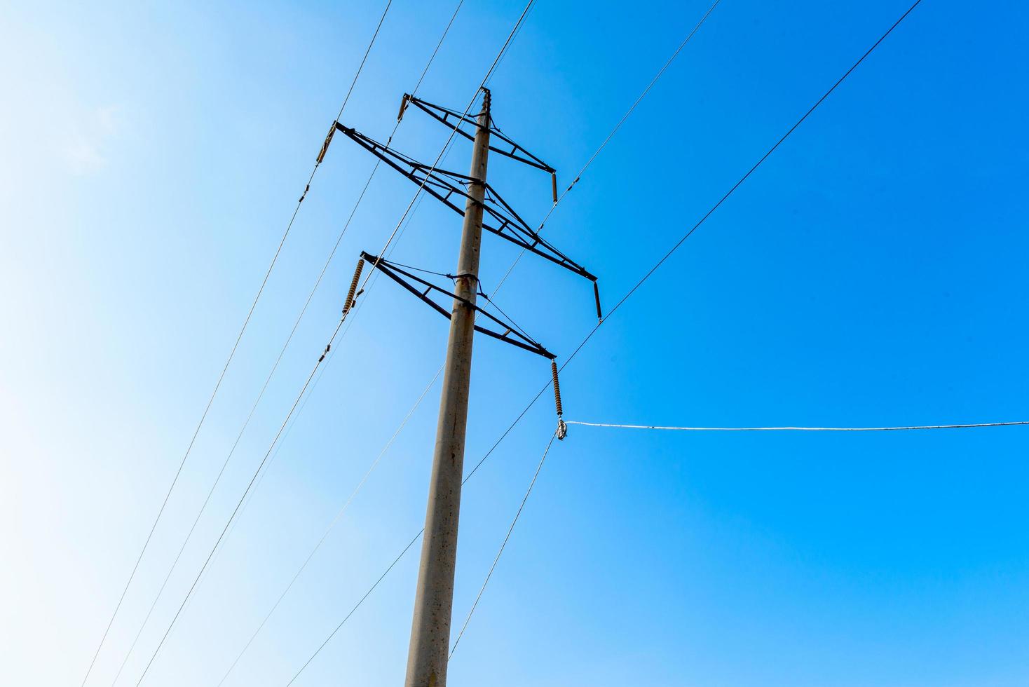 Línea de transmisión de alta tensión con soportes de hormigón en el fondo del cielo azul foto