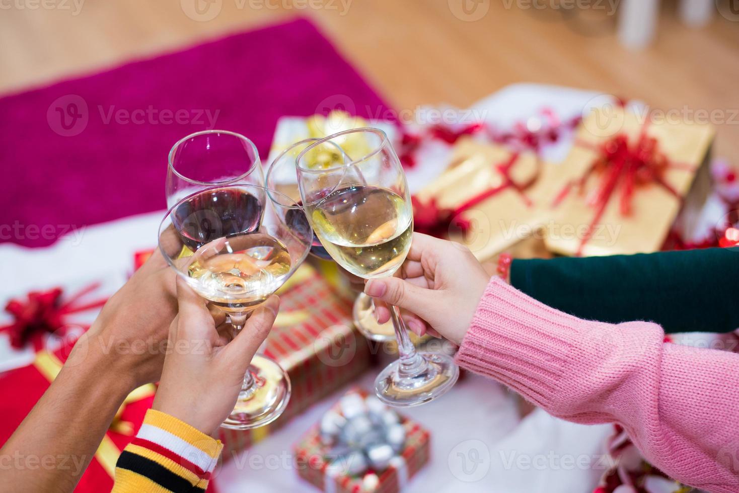 Manos de personas celebrando la fiesta de año nuevo en casa con vaso para beber foto