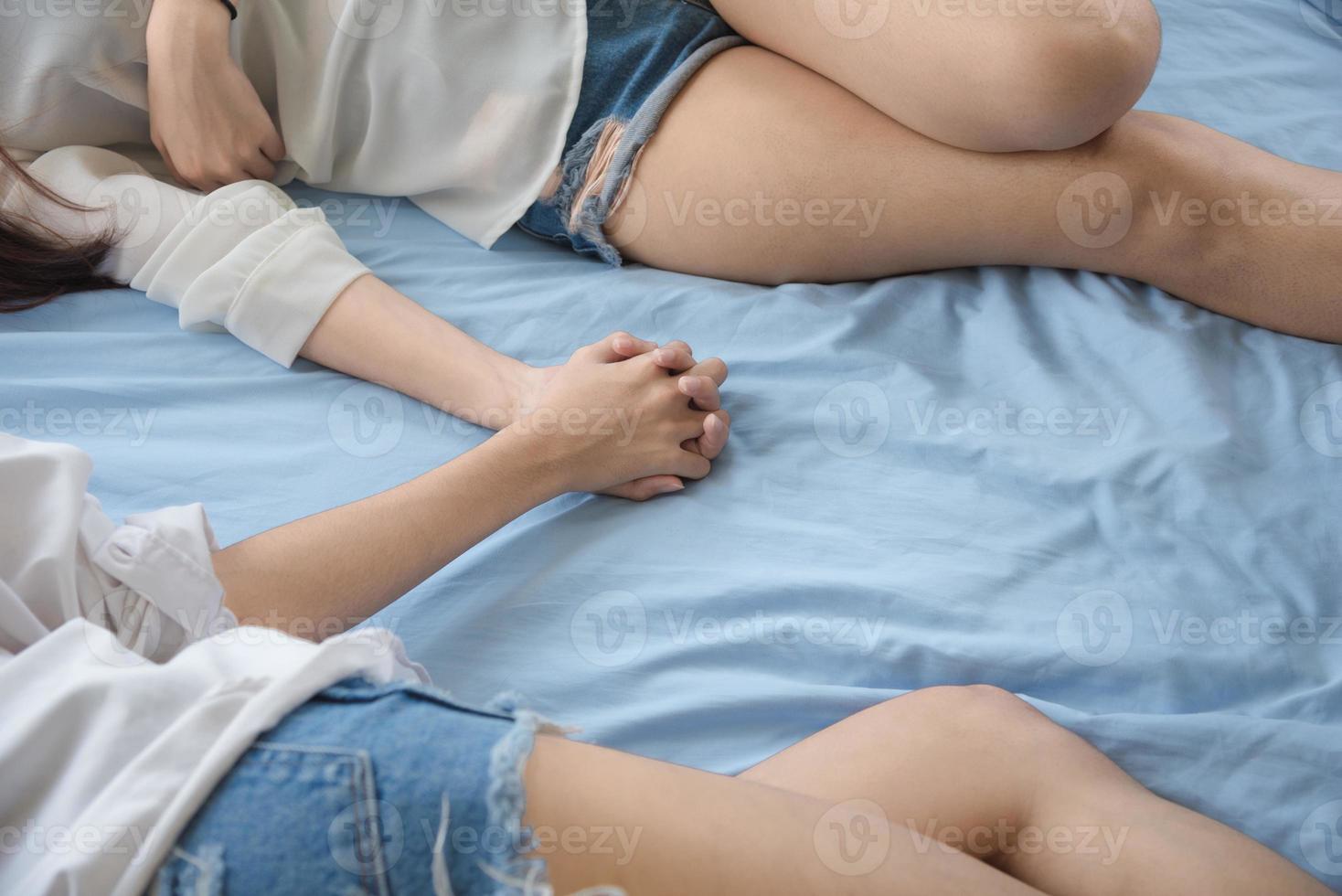 lesbianas durmiendo y tomados de la mano en la cama juntos foto