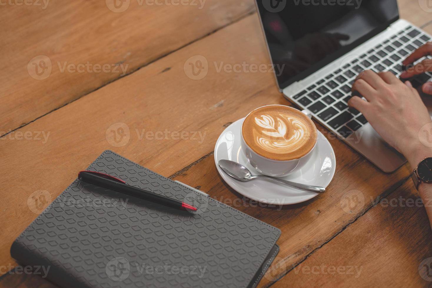 Cerca de la taza de café con portátil y manos de mujer con portátil foto