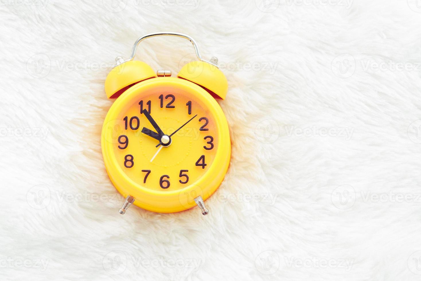 Yellow alarm clock on white wool. Late and Lazy time concept photo