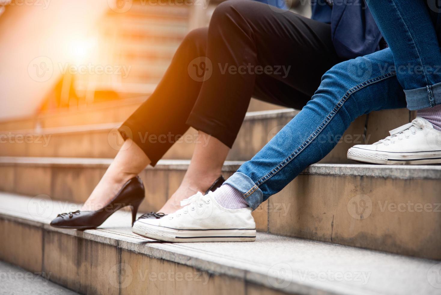 Close up of two woman legs. Friend are talking together on stair photo