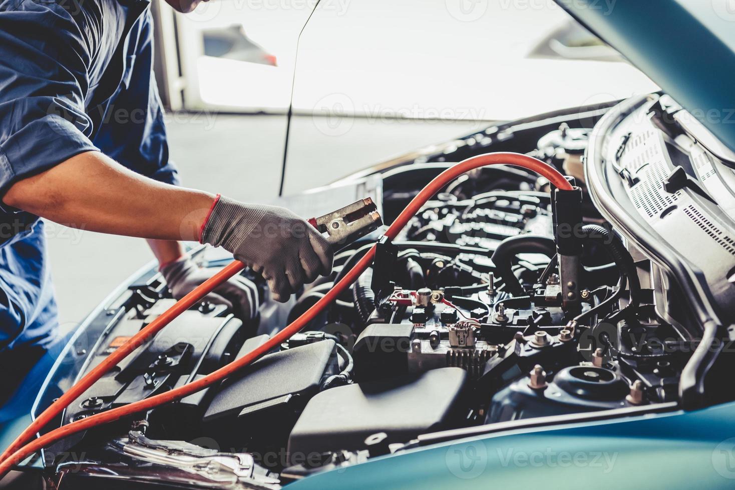 Car mechanic holding battery electricity trough cables jumper photo