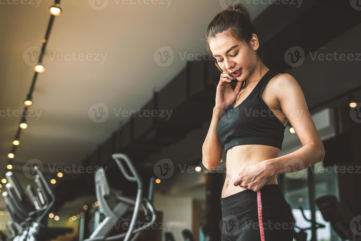 Sport happy slim woman using waist tape line in fitness gym photo