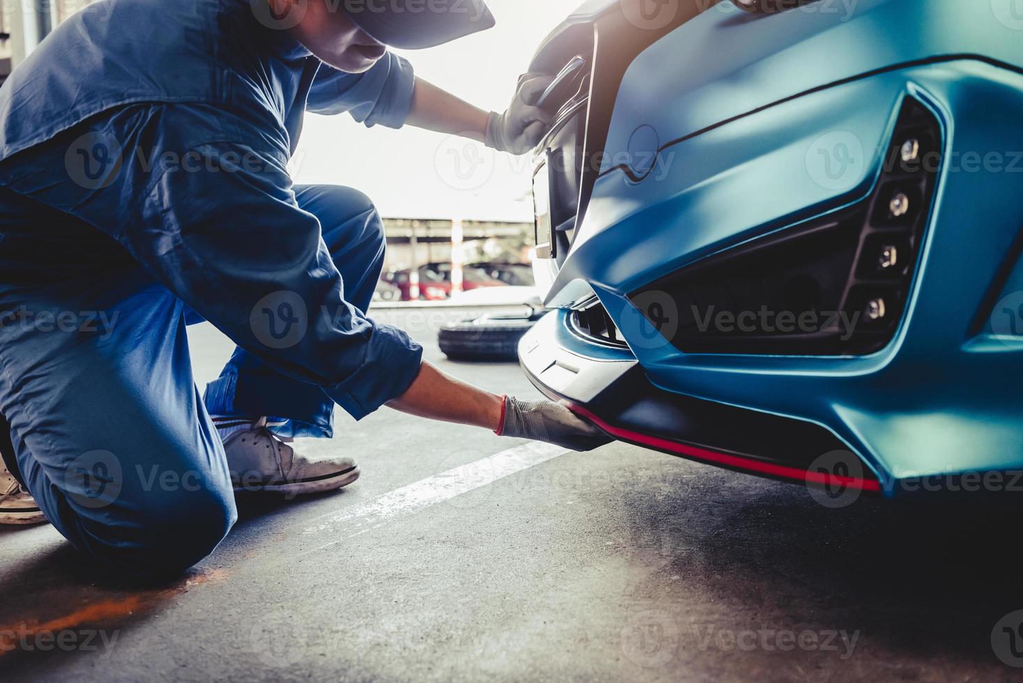 Mecánicos instalando faldón delantero en el garaje del taller de reparación de automóviles foto