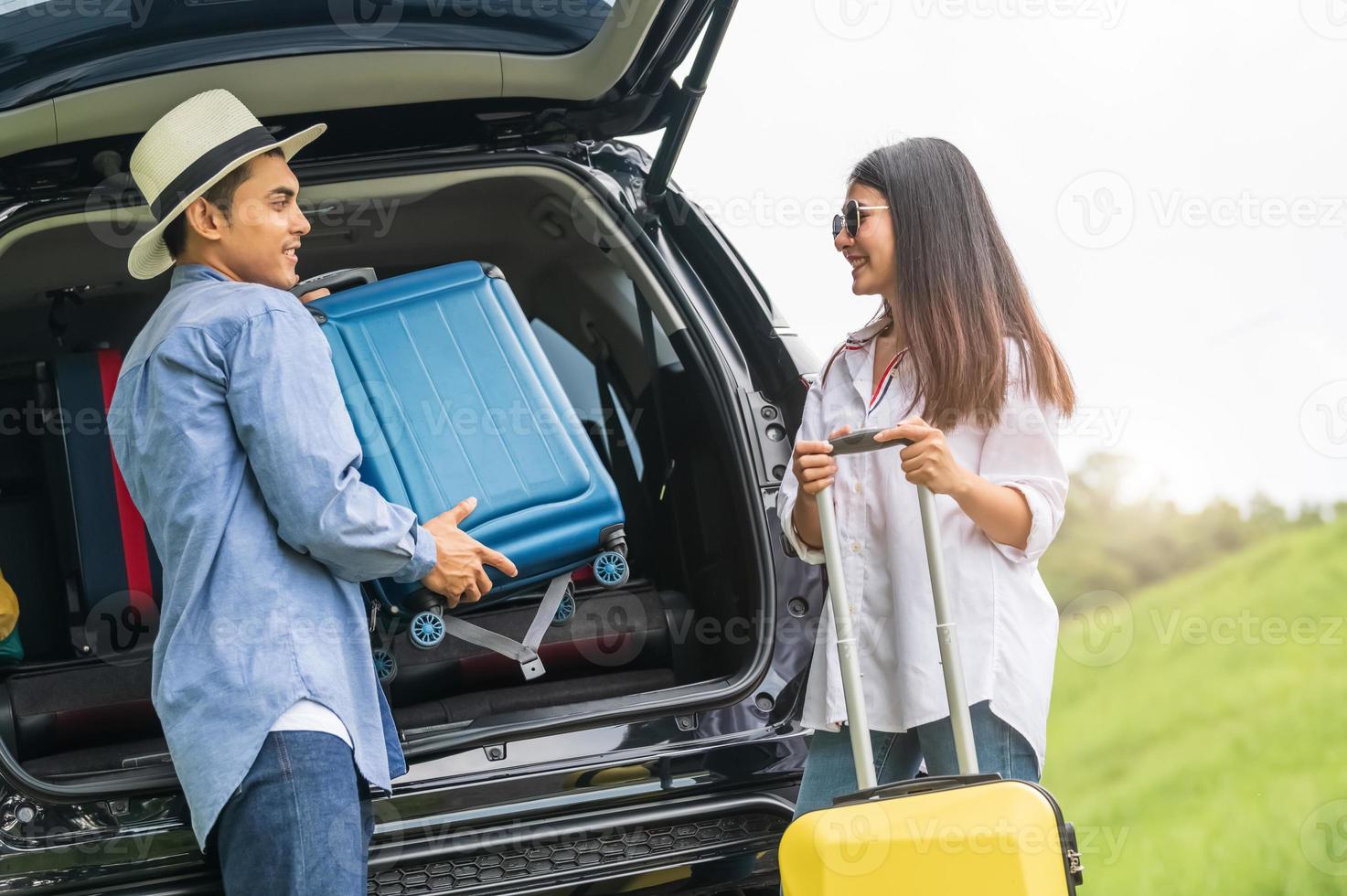Hombre asiático ayudando a la mujer a levantar la maleta del coche foto