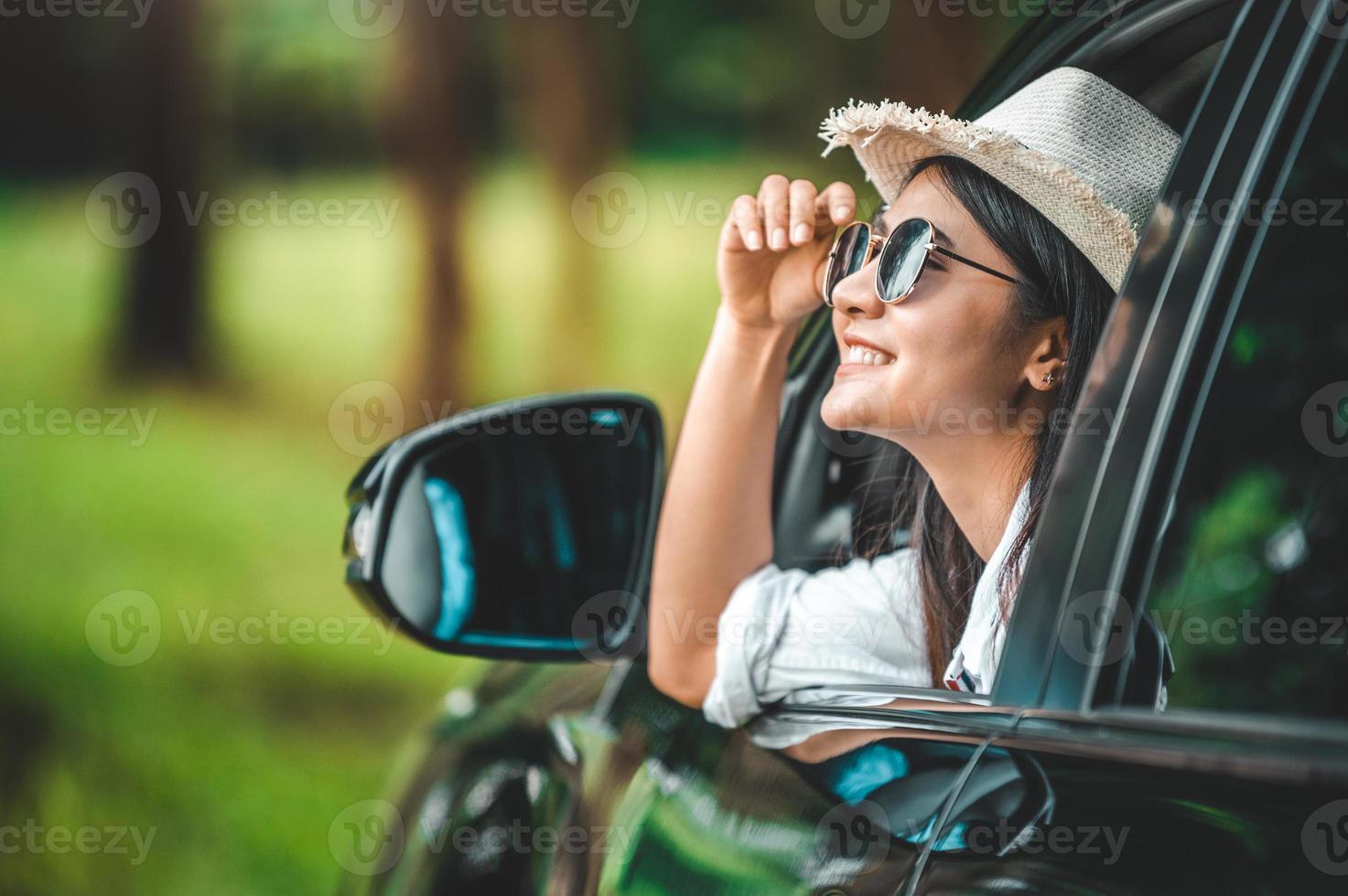 Happy woman hand holding hat outside open window car photo