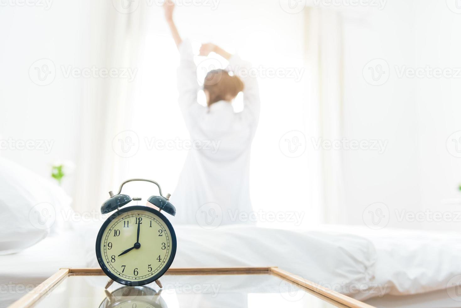 Back view of woman stretching in morning after waking up on bed photo