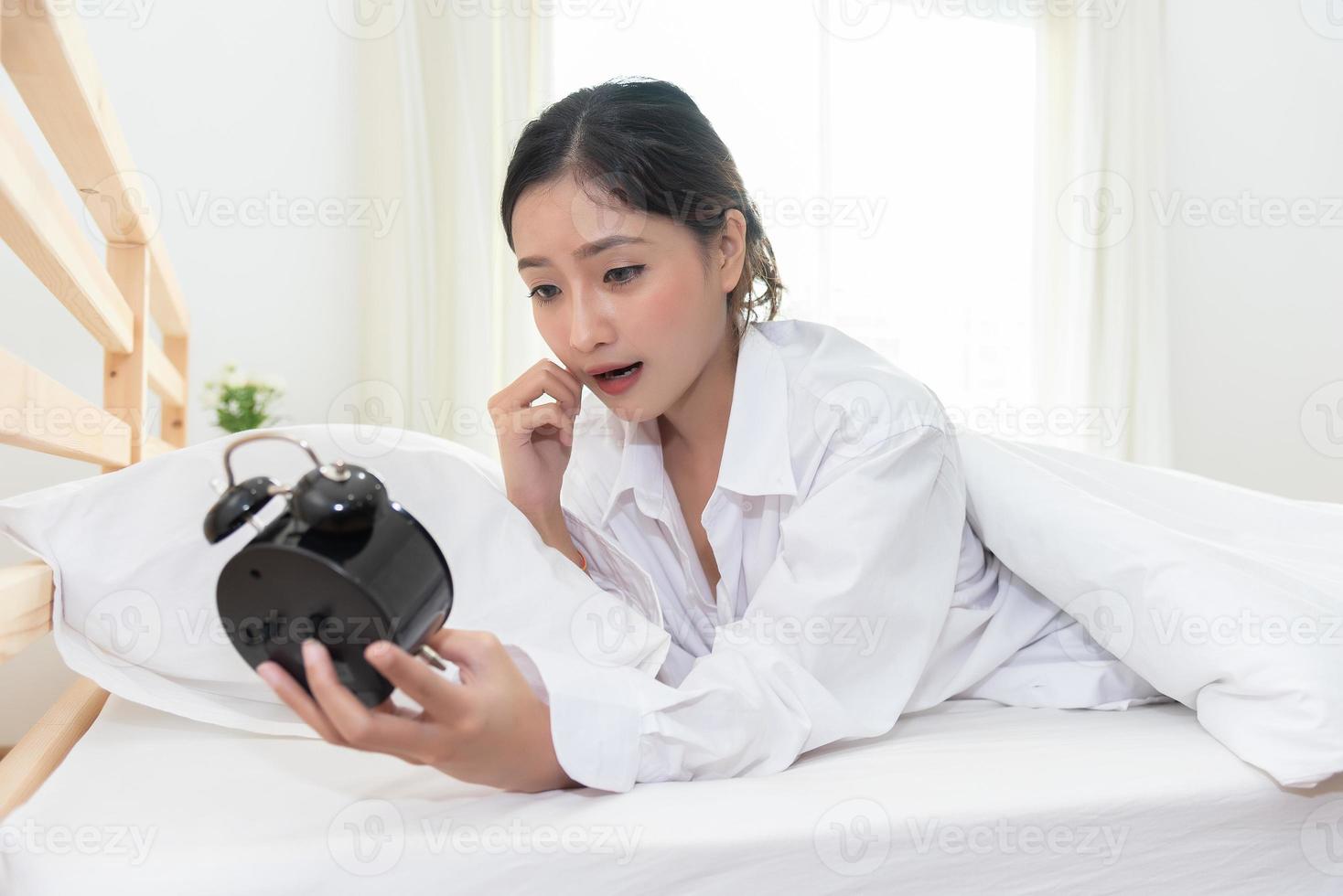 Asian woman shocked when wake up late by forget to setting alarm photo