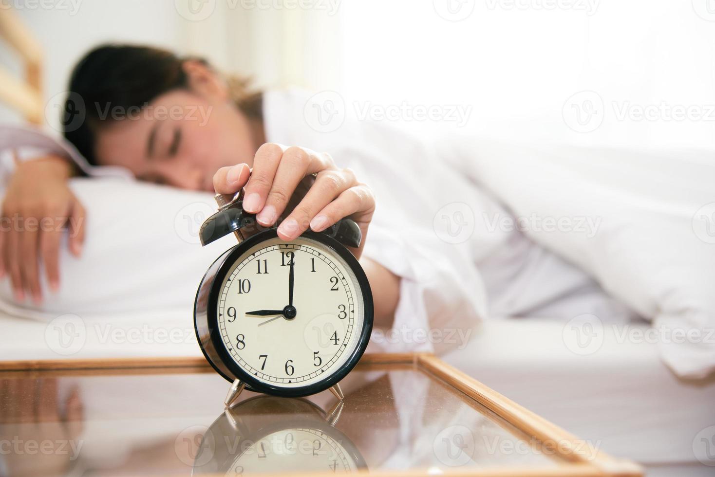 Asian young beauty woman turning off alarm clock in morning photo