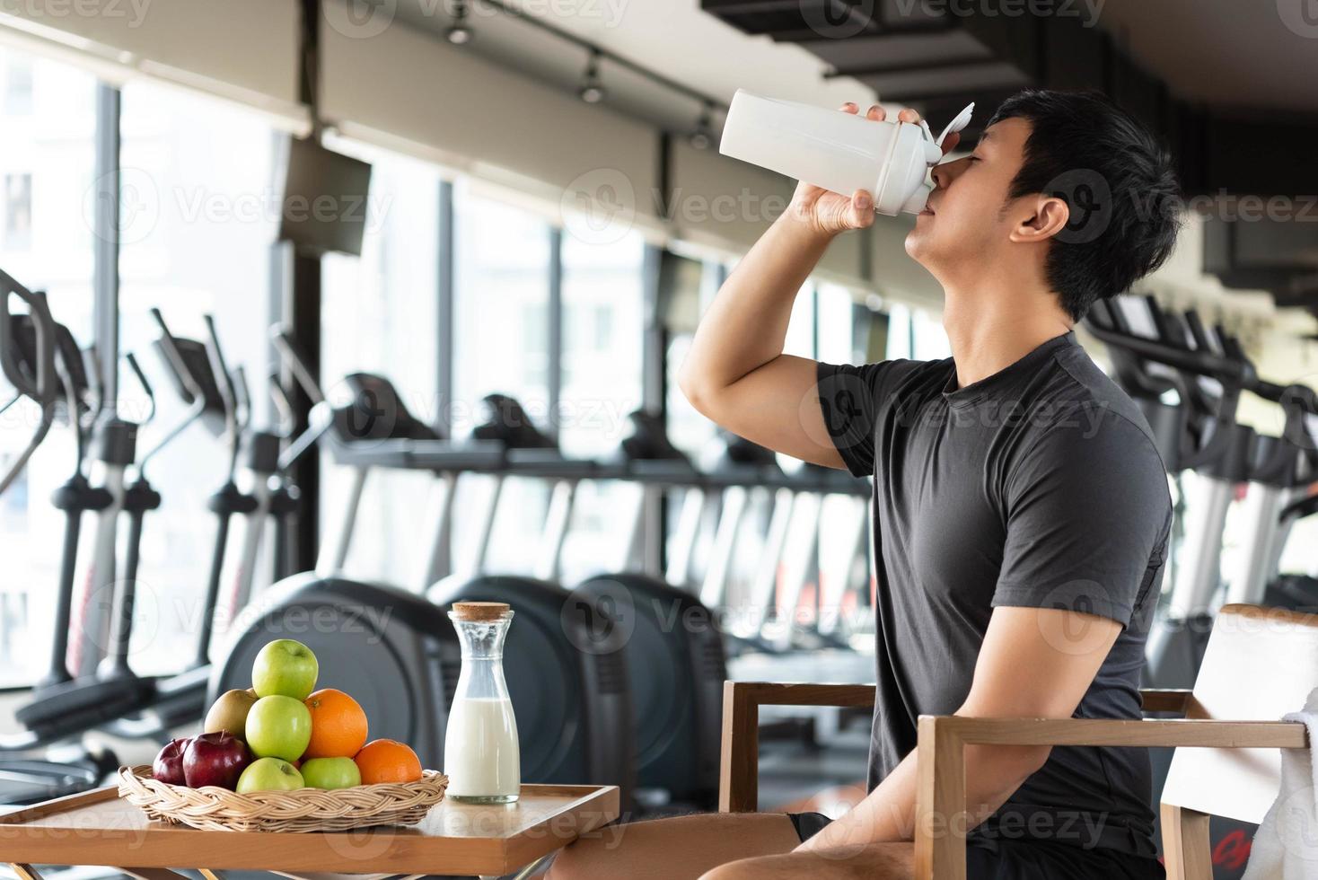 Hombre guapo bebiendo batido de proteínas, leche y muchos tipos de frutas. foto