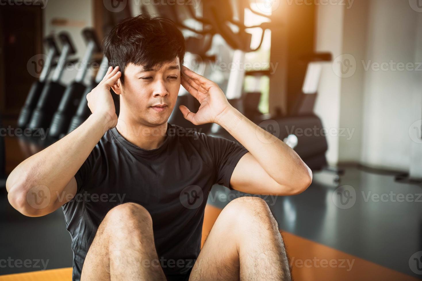 Hombre de deporte asiático haciendo abdominales o sentadillas en una estera de yoga foto