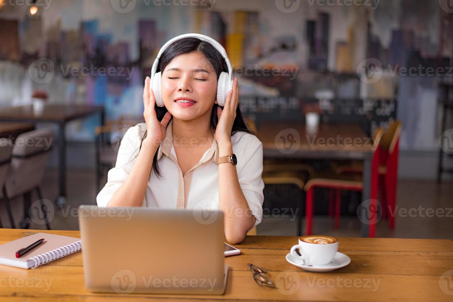 Hermosa mujer asiática relajarse y escuchar música en el café foto