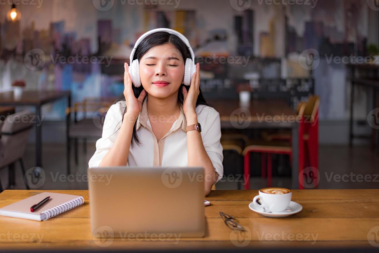 Hermosa mujer asiática relajarse y escuchar música en el café foto