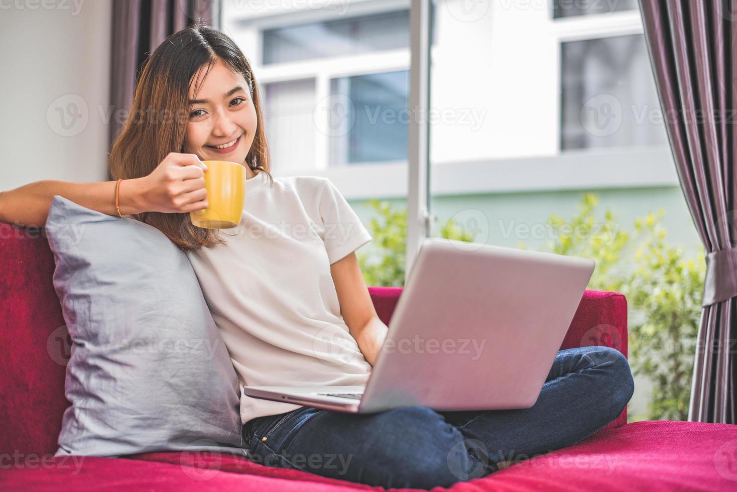 Mujer asiática disfrutar mientras usa internet en un portátil y un teléfono foto
