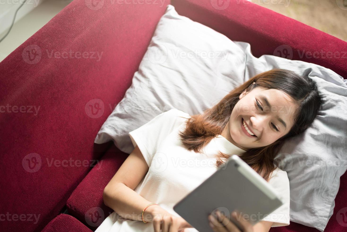 Woman enjoy relax at home with tablet on red sofa photo