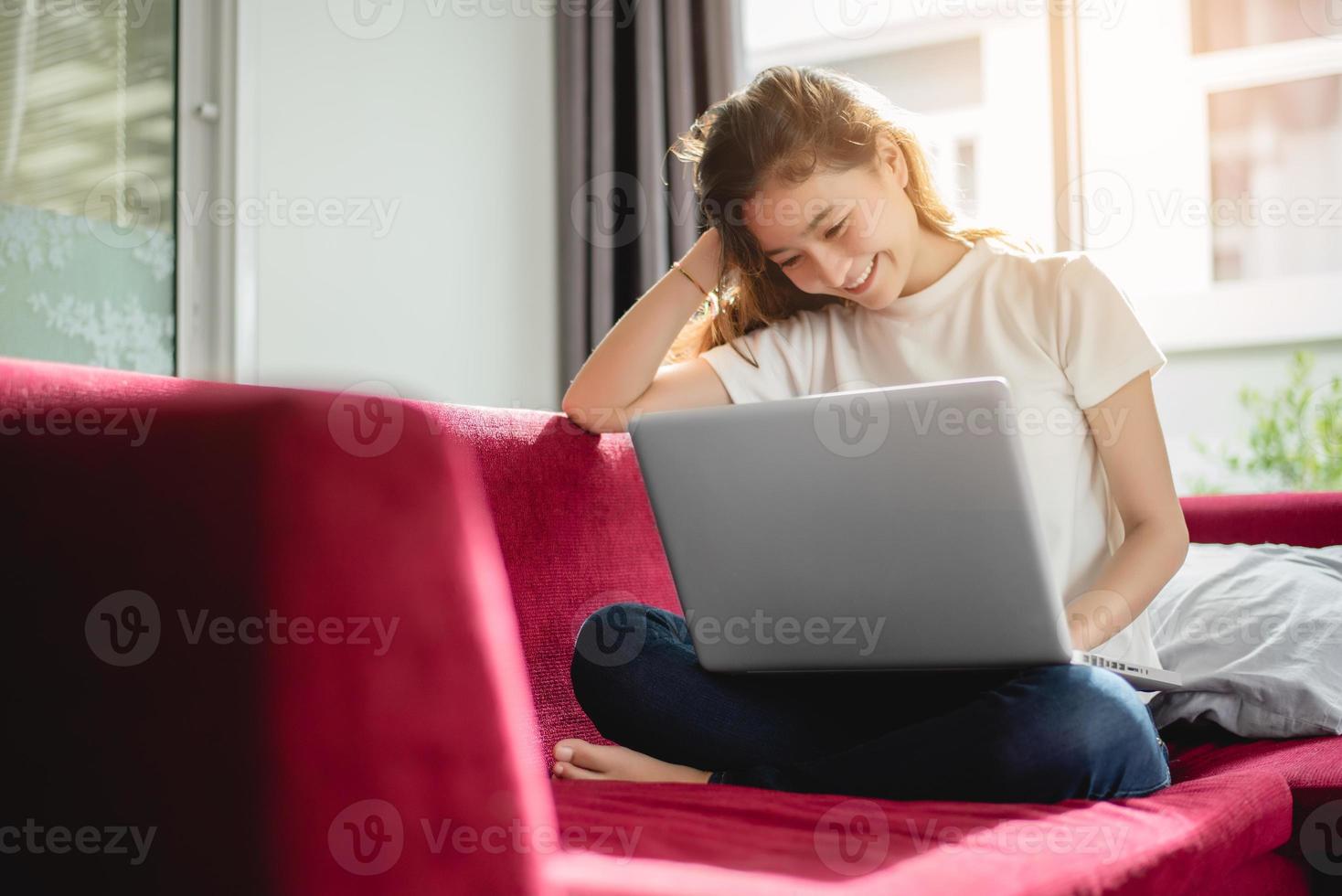 Young woman shopping online with internet in happy mood on red sofa photo