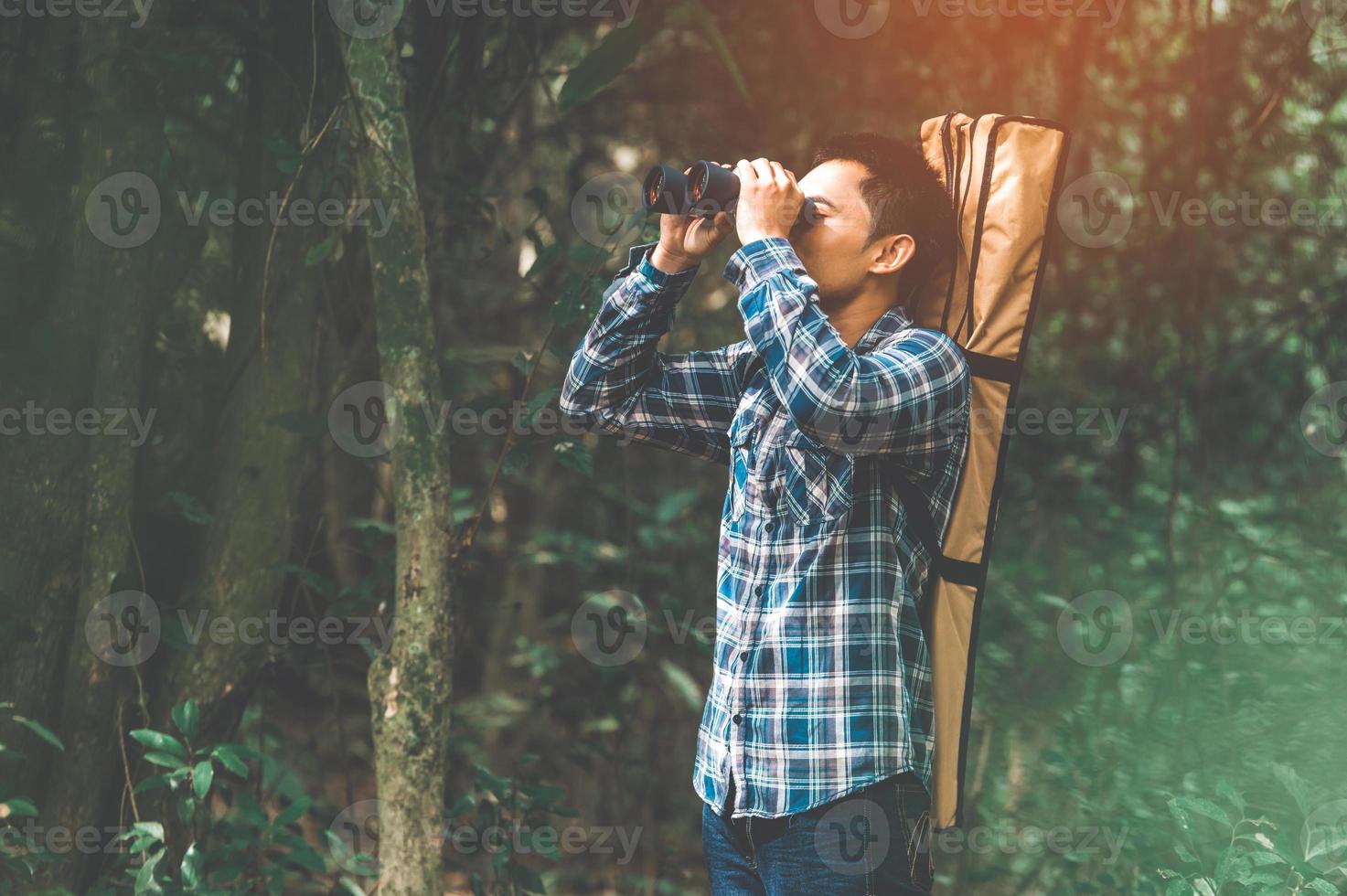 Hombre con telescopio binoculares en el bosque en busca de destino foto