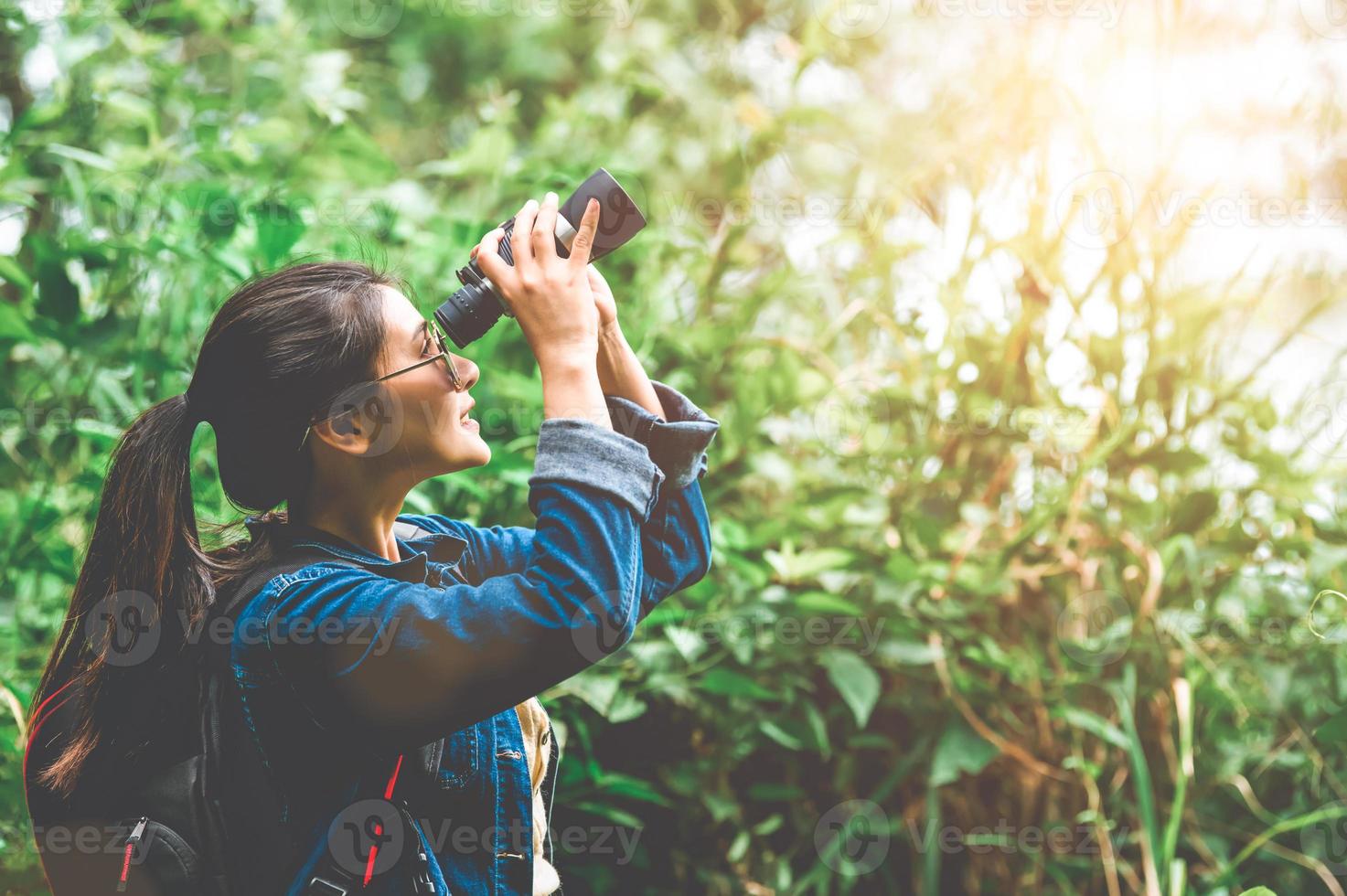 Hermosa mujer asiática con telescopio binoculares en el bosque foto