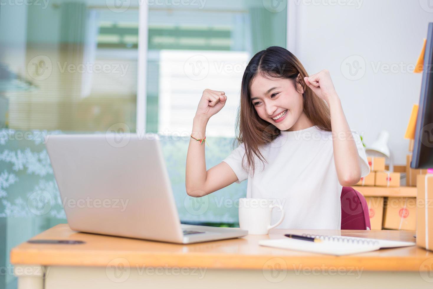Mujer asiática disfrutar mientras usa computadoras portátiles e internet en la oficina foto