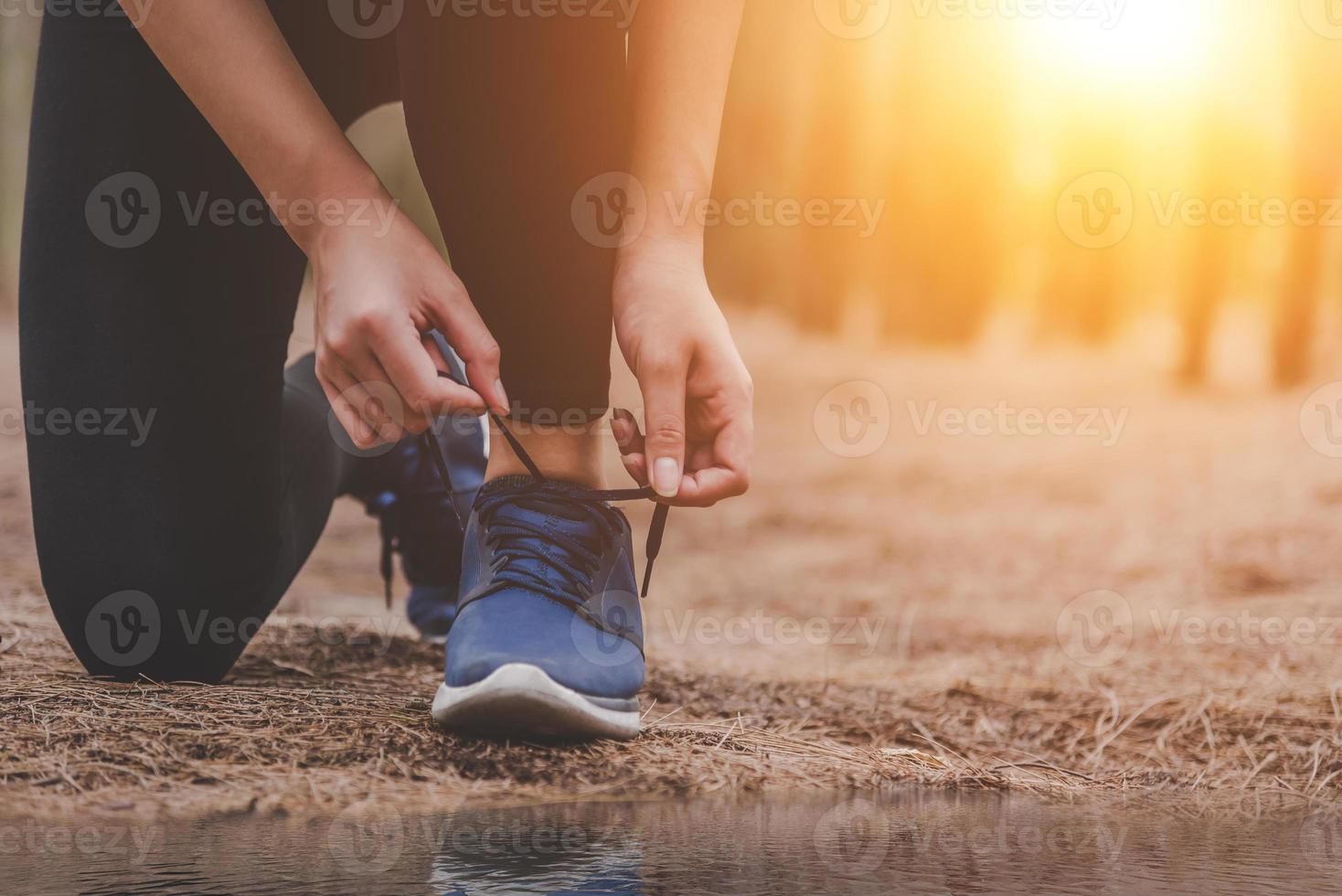 Joven mujer corriendo fitness atar cordones de los zapatos al aire libre en el bosque foto