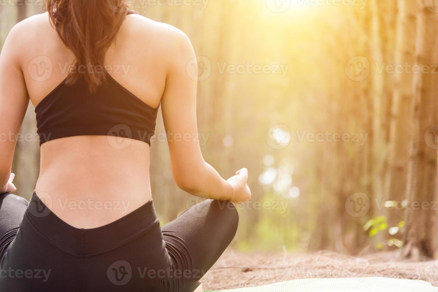 Back view of beautiful woman doing yoga pose in peaceful forest photo