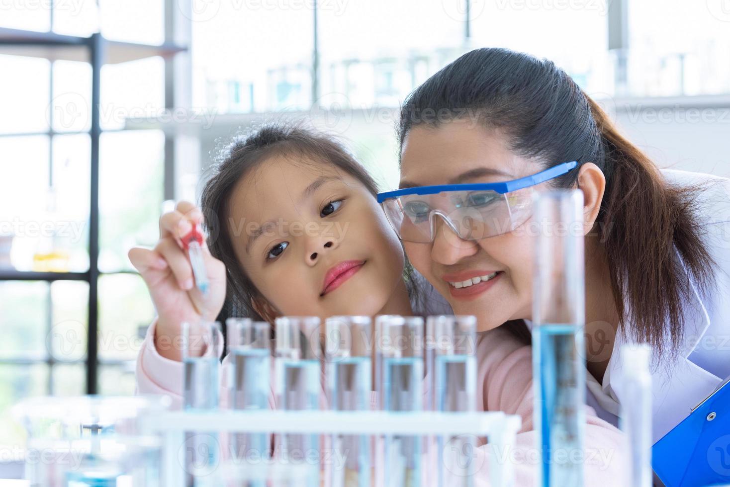 niña científica y maestra soltando solución sustancia pipeta líquida foto