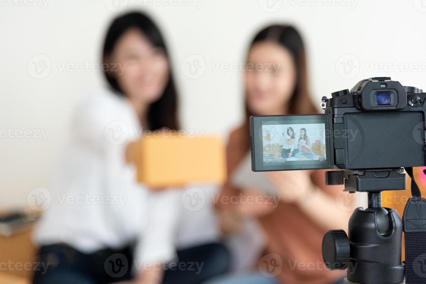 Closeup of digital video camera recording two girls presenting photo