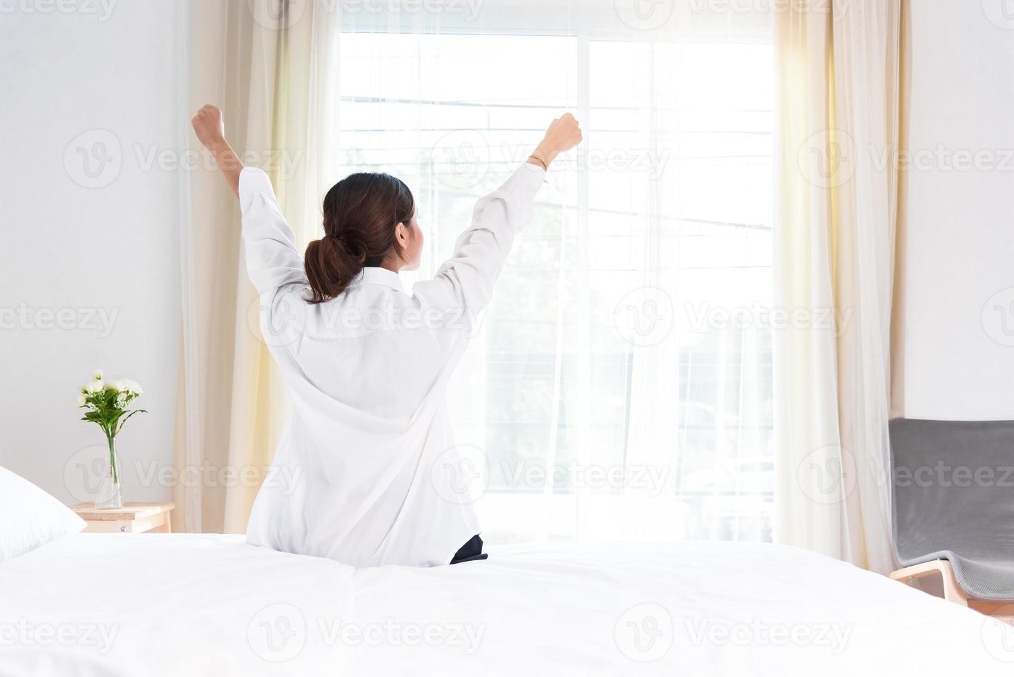 Back view of woman stretching in morning after waking up on bed photo