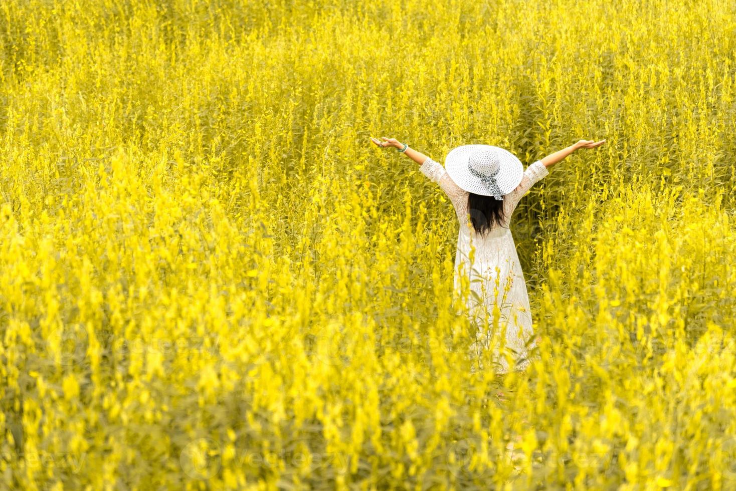 Back view of woman with white wing hat and dress in flower meadow photo