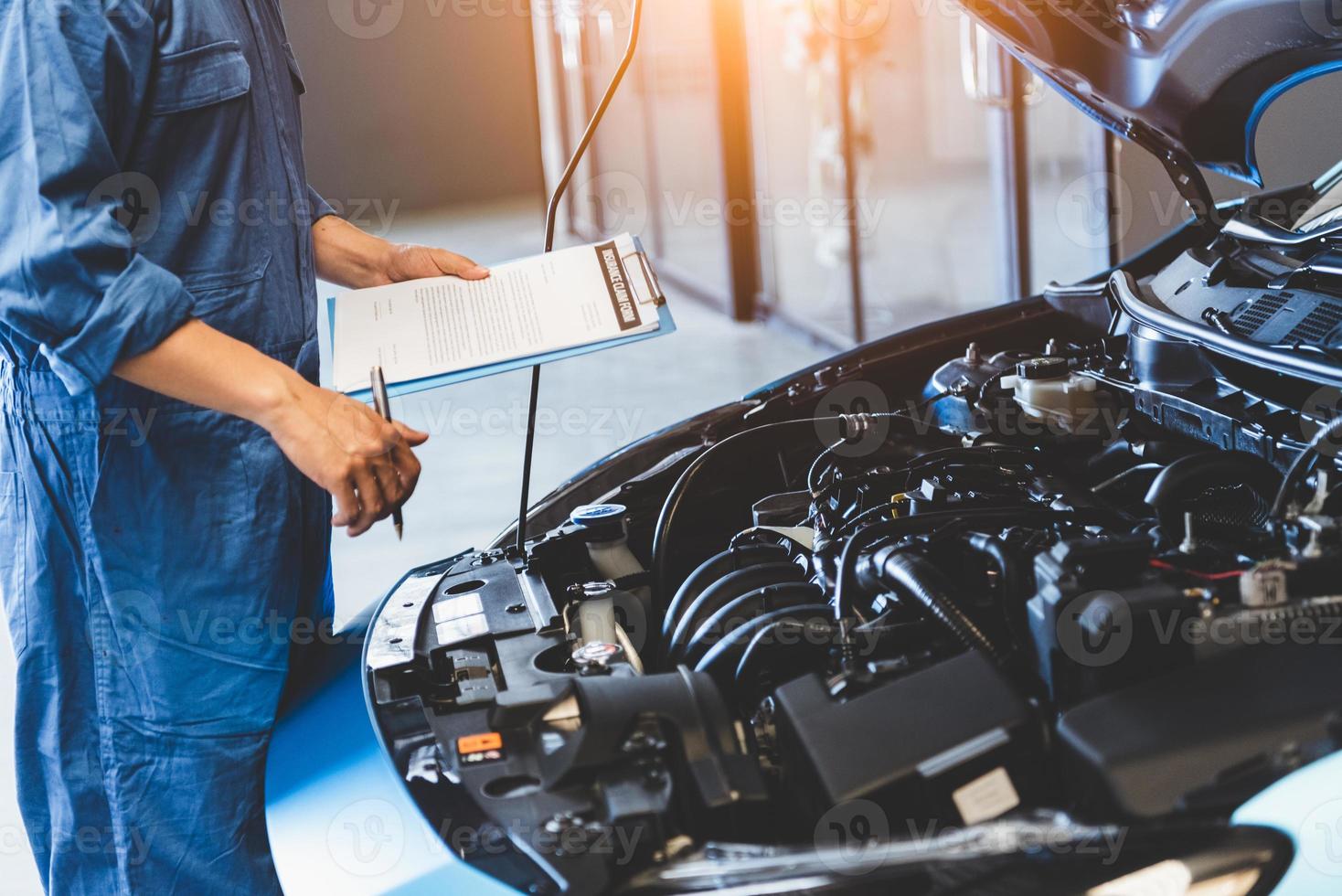 Car mechanic holding clipboard and checking to maintenance vehicle photo