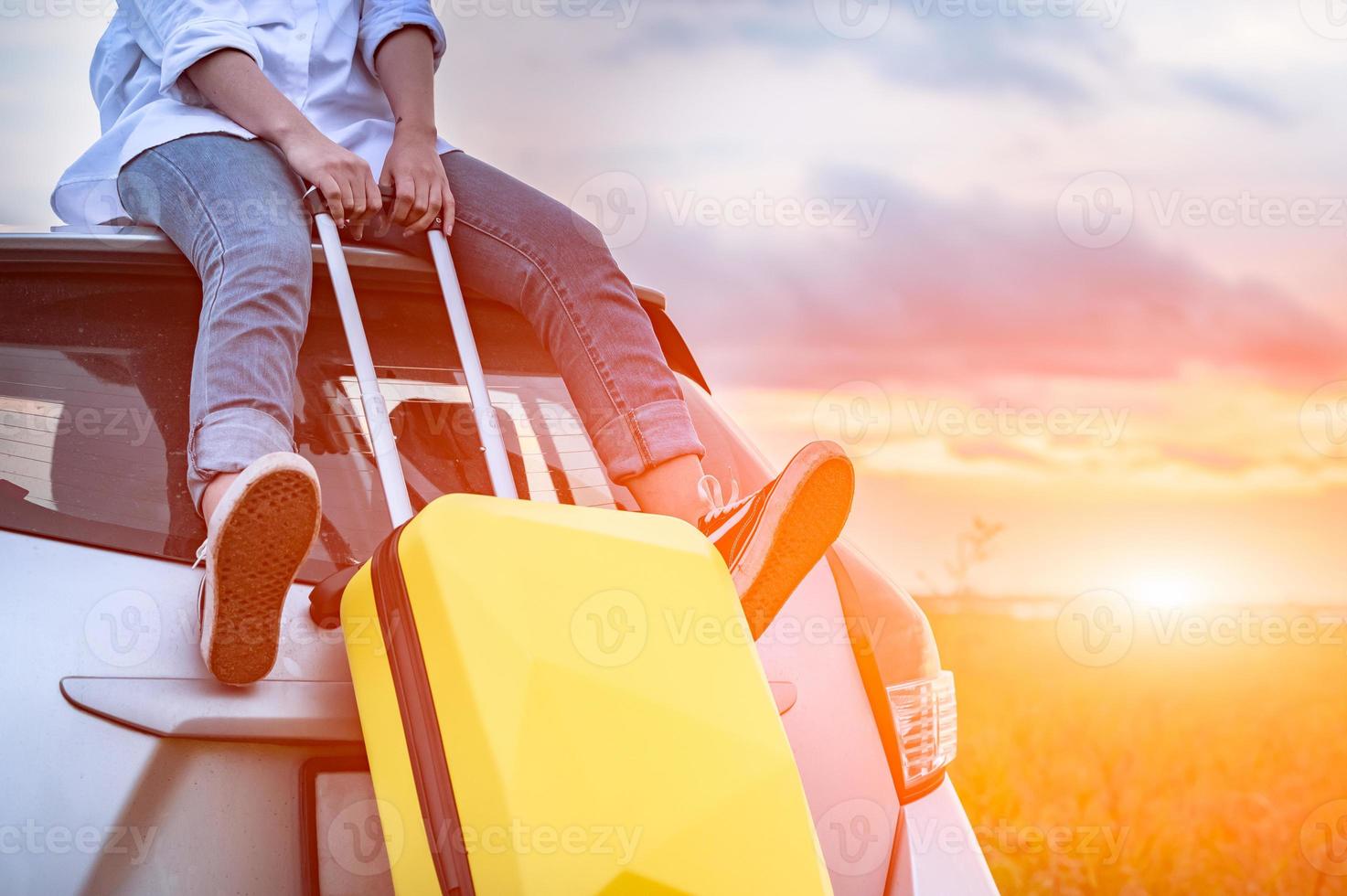 Closeup of happy Asian woman on top of car with luggage bag photo
