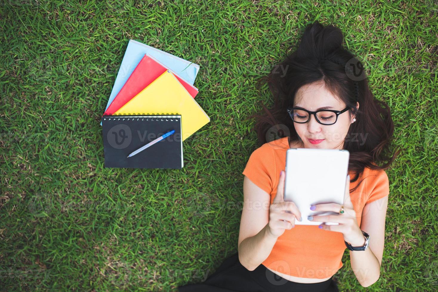 Happy Asian woman using tablet when relaxing in park photo