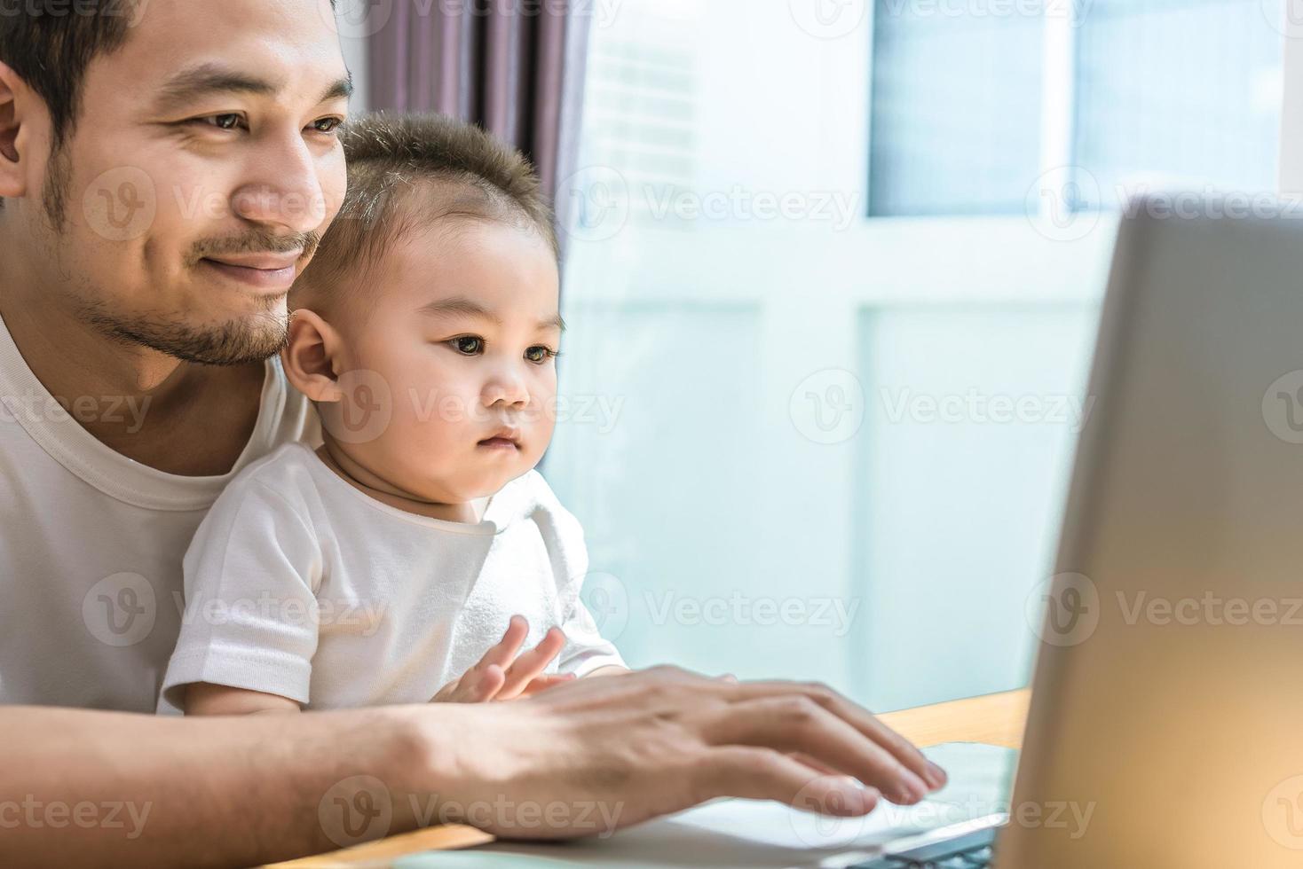 Single dad and son using laptop together happily photo