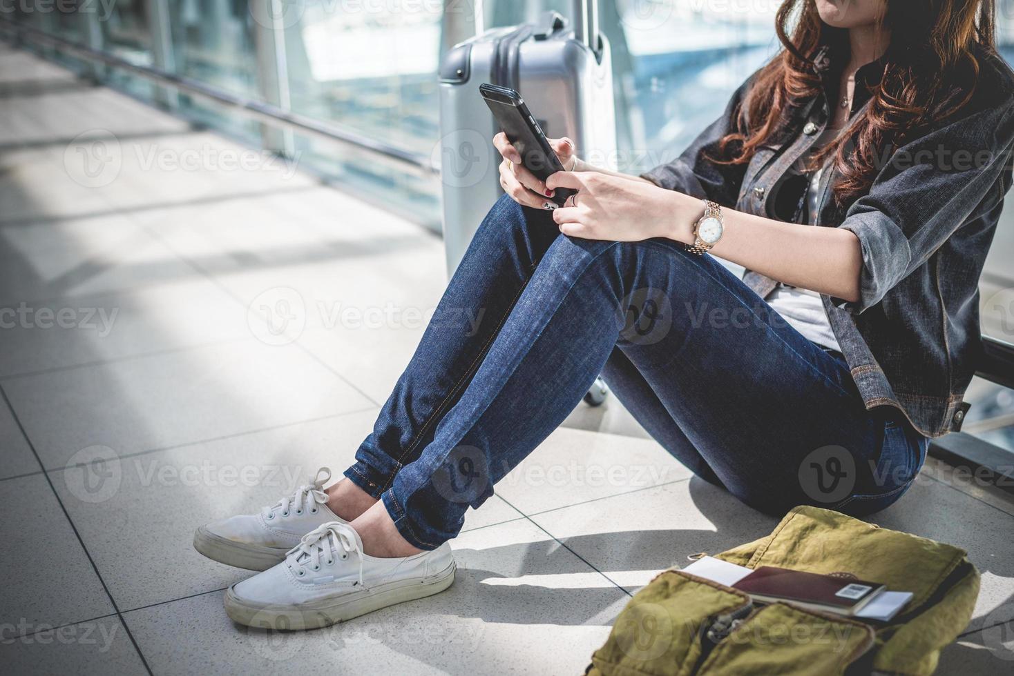 Cerca de la mujer con el bolso y la maleta de equipaje esperando la salida foto