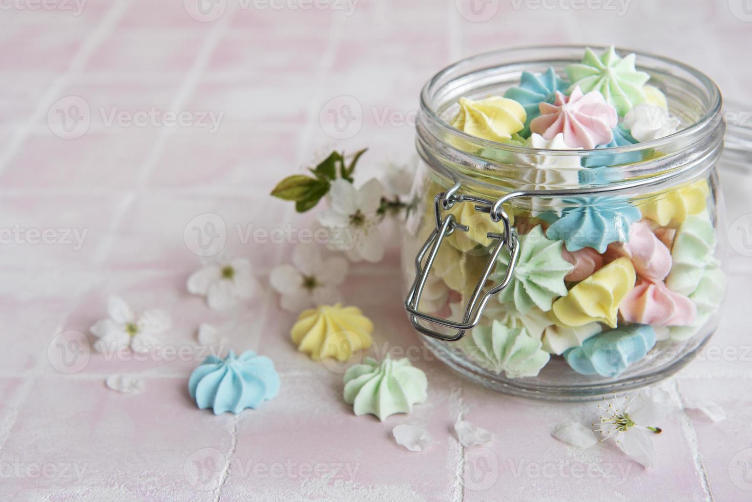 Small colorful meringues in the glass jar photo