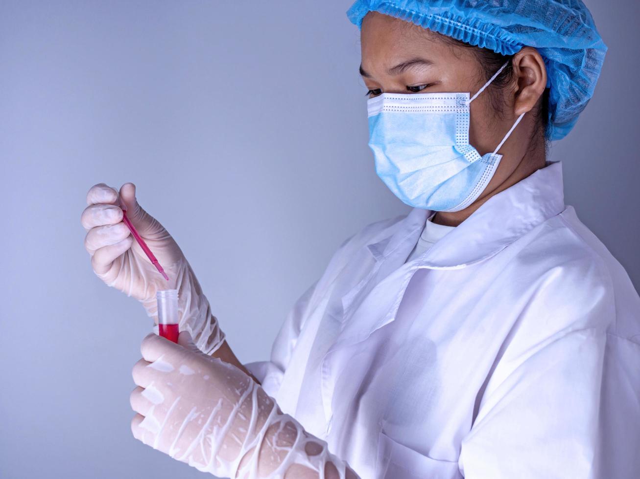 Woman chemist holds flask with red liquid in her hands photo