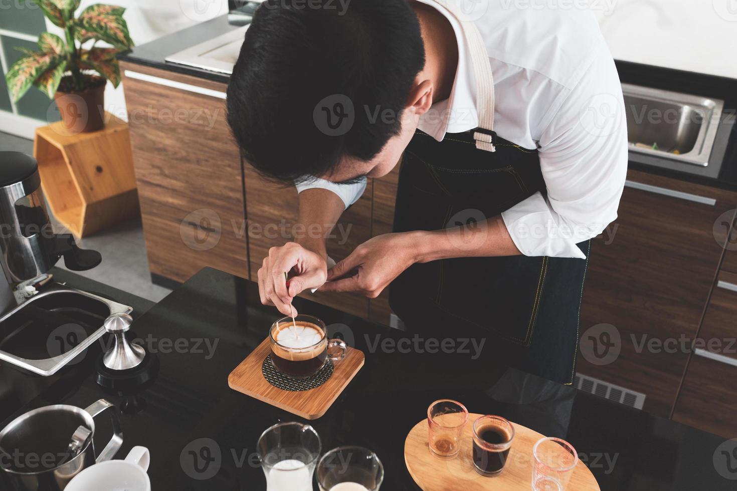 Joven barista haciendo arte café con leche en el café foto