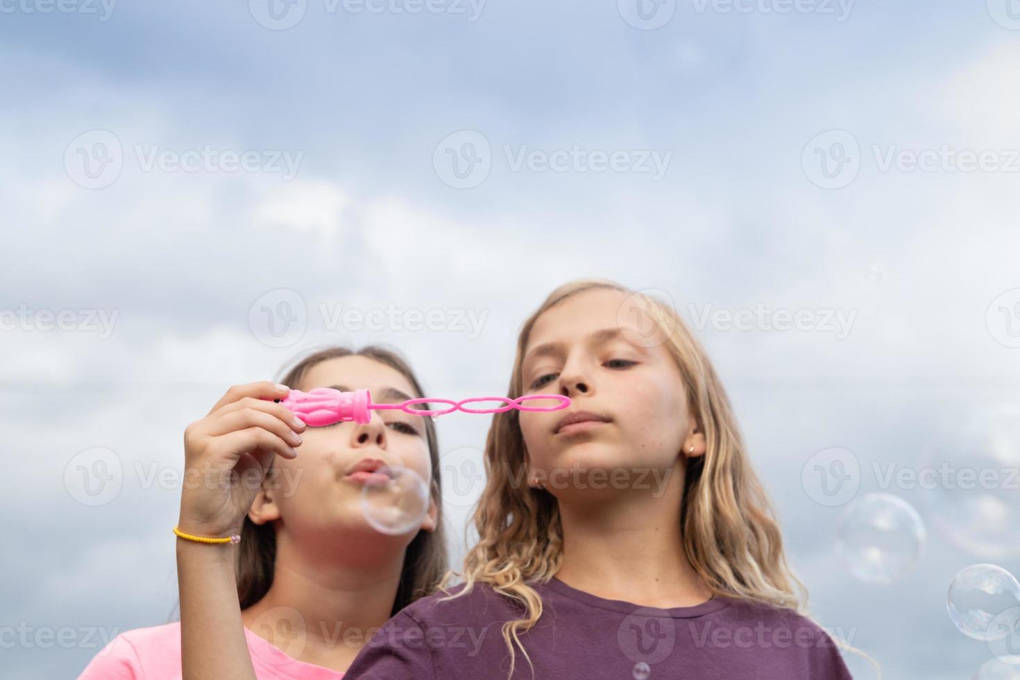 Two girls blowing soap bubbles photo