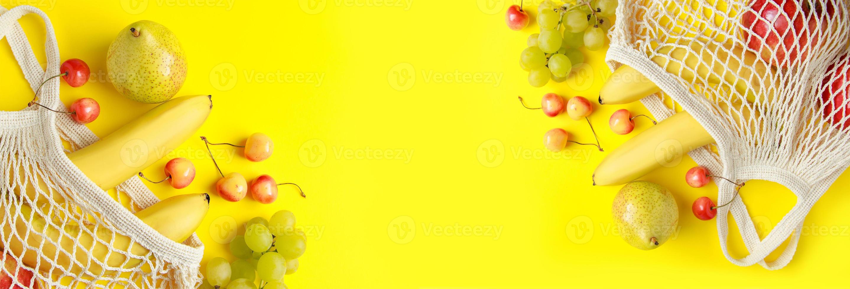 Ripe fruits in mesh bag on yellow background. photo