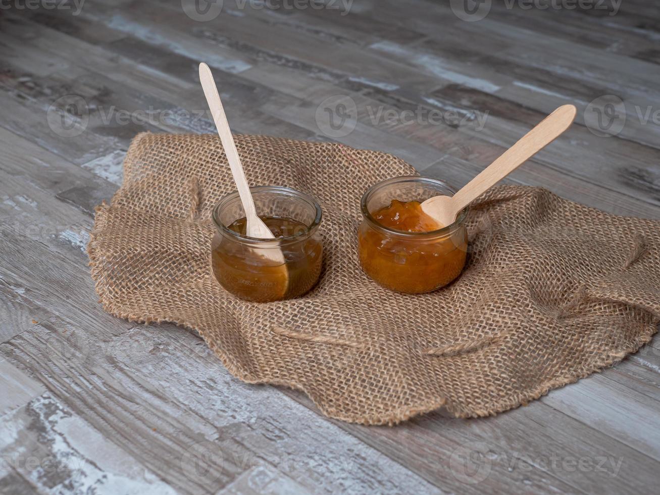 Mermelada en un frasco de vidrio con cuchara de madera en el interior, concepto de comida ecológica foto