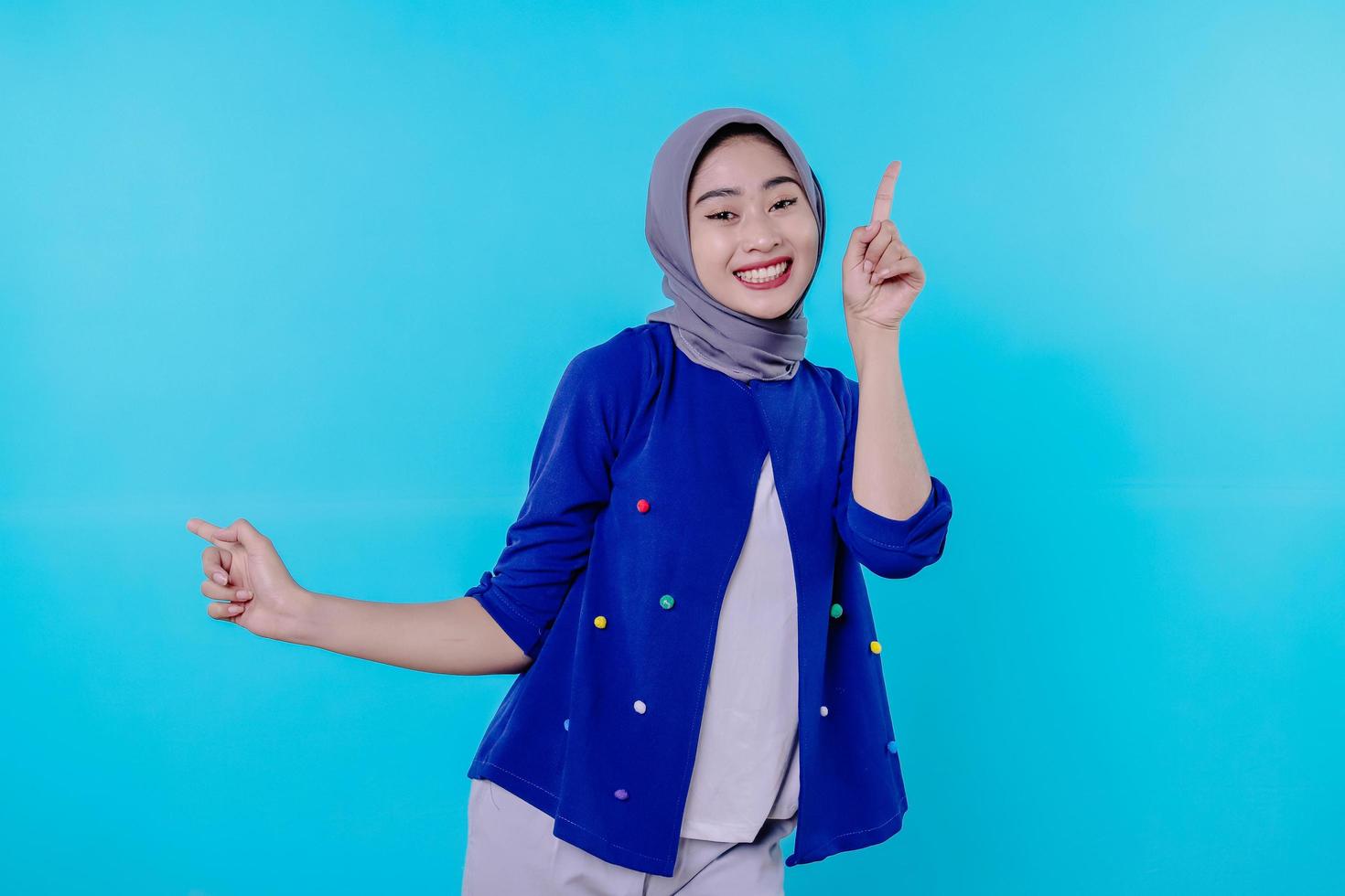 Good looking charismatic young woman with wearing hijab pointing photo